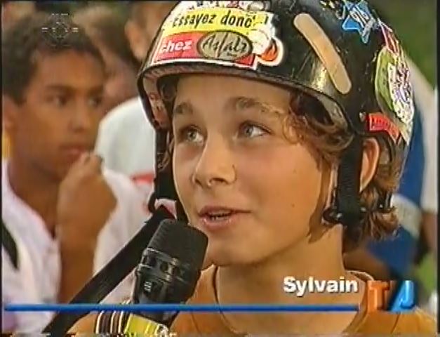 Sylvain enfant, casque couvert d’autocollants, interviewé au Téléjournal en 1995